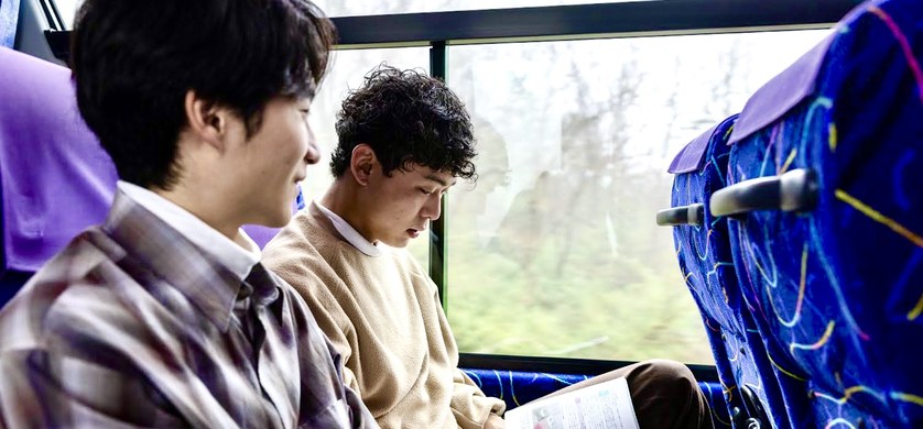 バスの車内で教材を読む学生たち