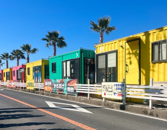 カラフルなコンテナハウスが並ぶ海沿いの道路	