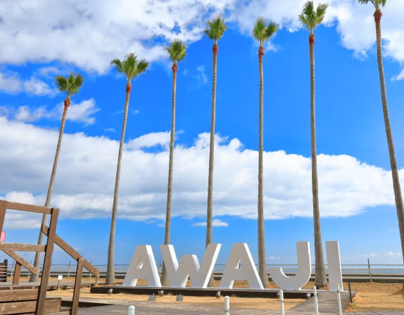 青空にそびえるヤシの木とAWAJIのモニュメント	